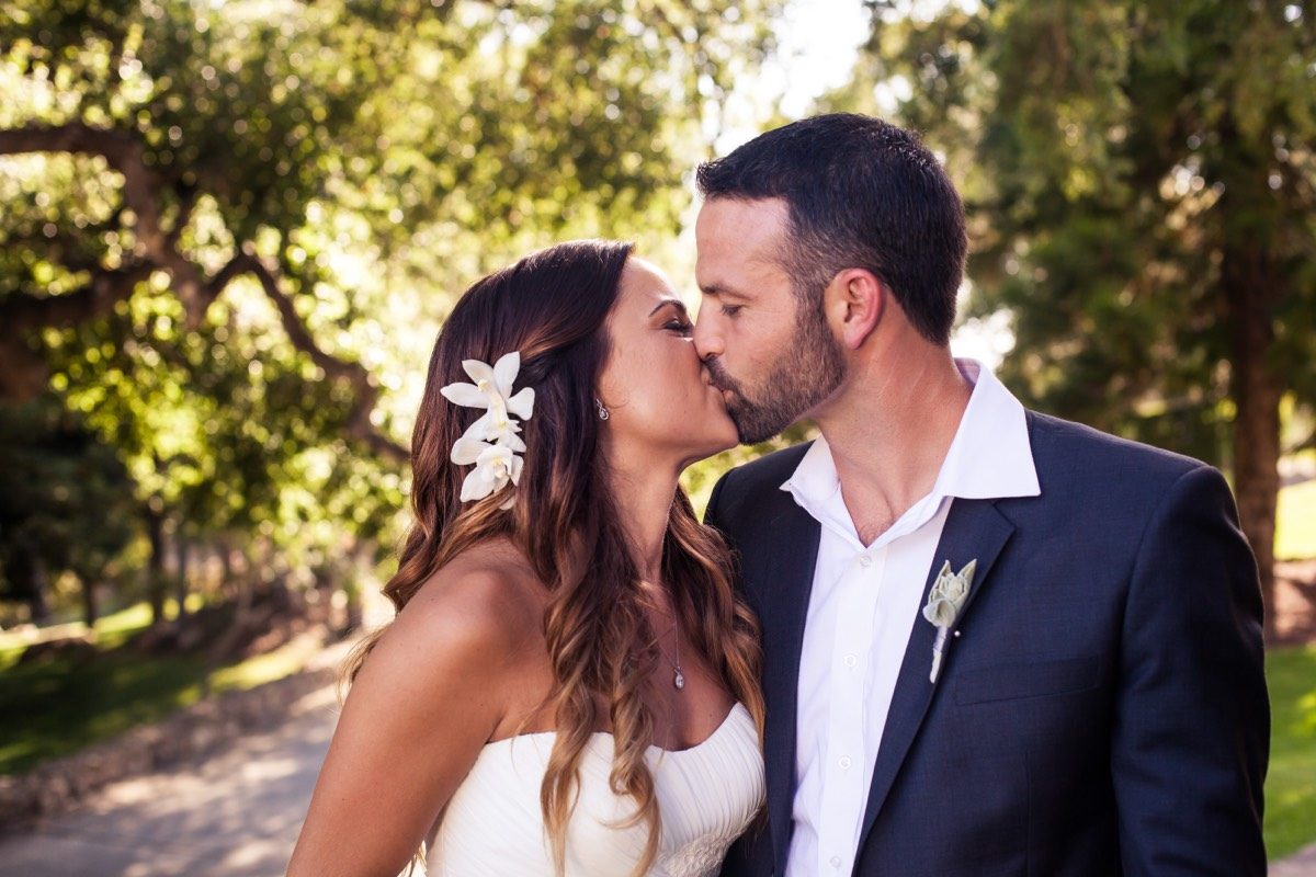Bride and groom kissing beneath oak trees on their wedding day