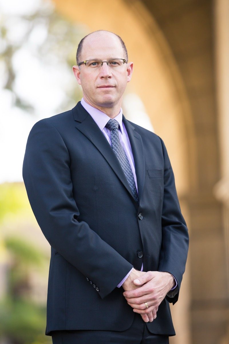 Man in a suit standing beneath a stone archway