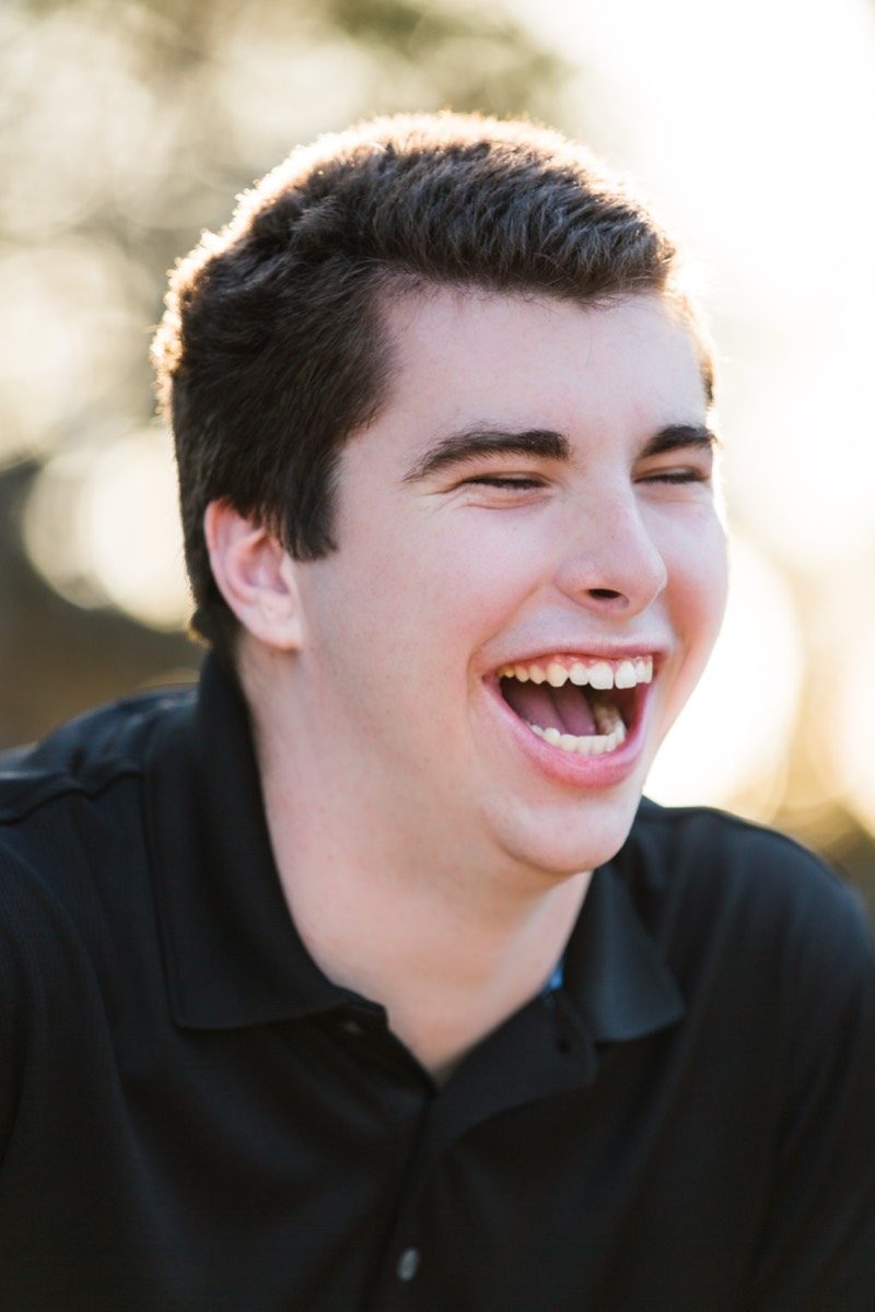 Senior laughing in front of a dark background