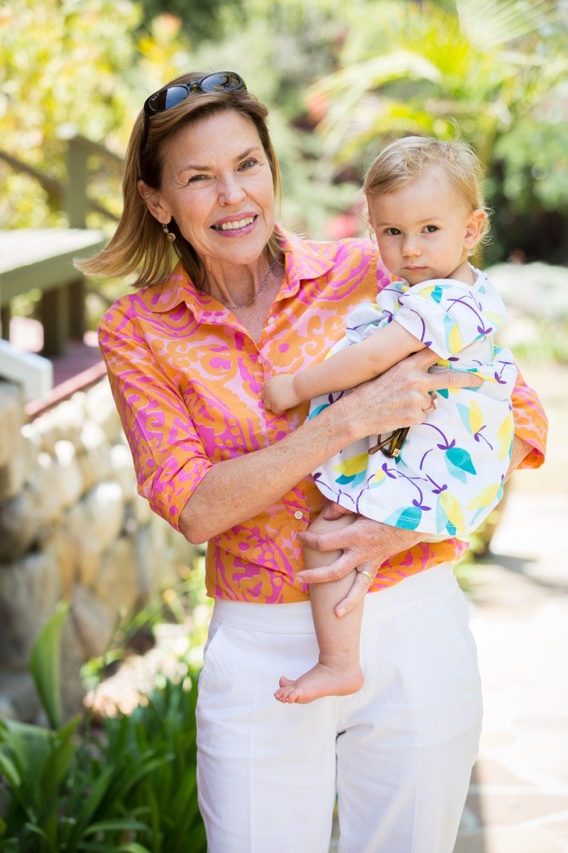 Woman in a coral blouse holding a baby on her hip in warm afternoon garden light