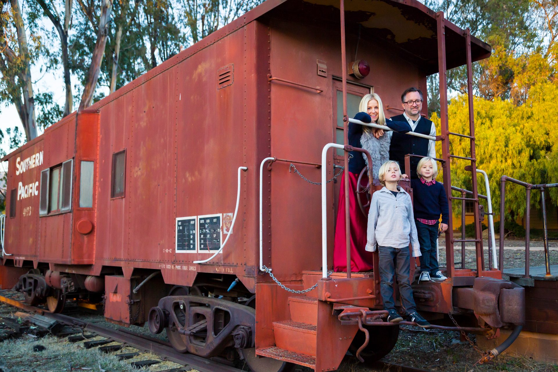 Family gathered on the steps of a red train caboose