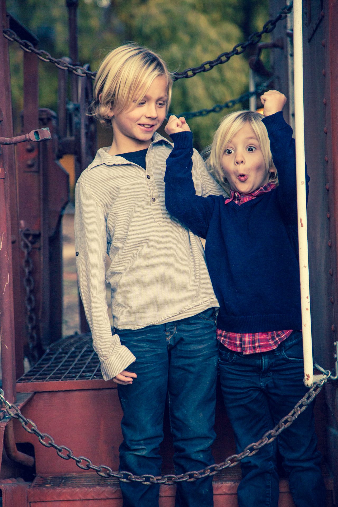 Two young brothers grinning on the platform of a red caboose