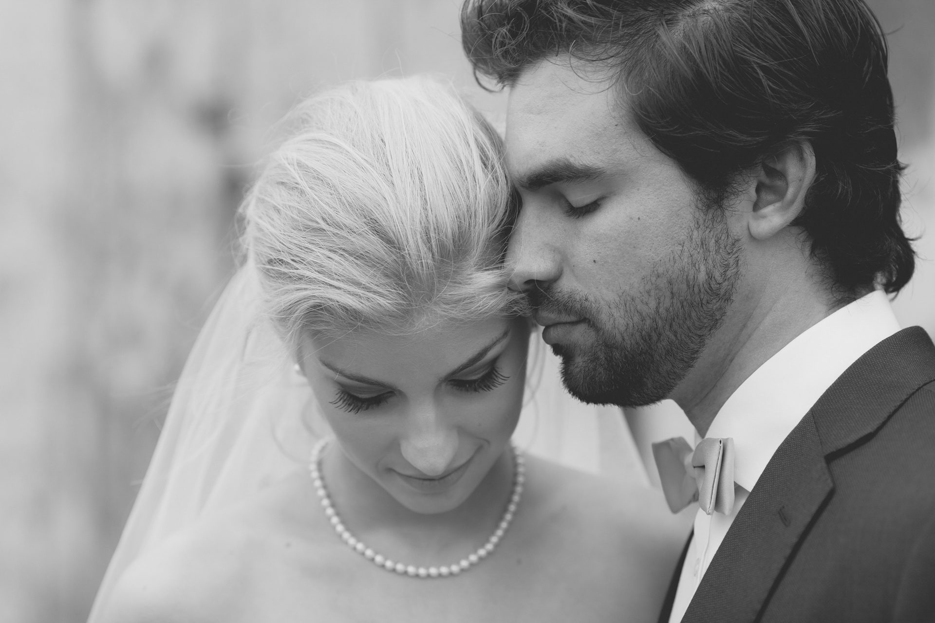 Black and white close portrait of a groom resting his forehead against his bride's