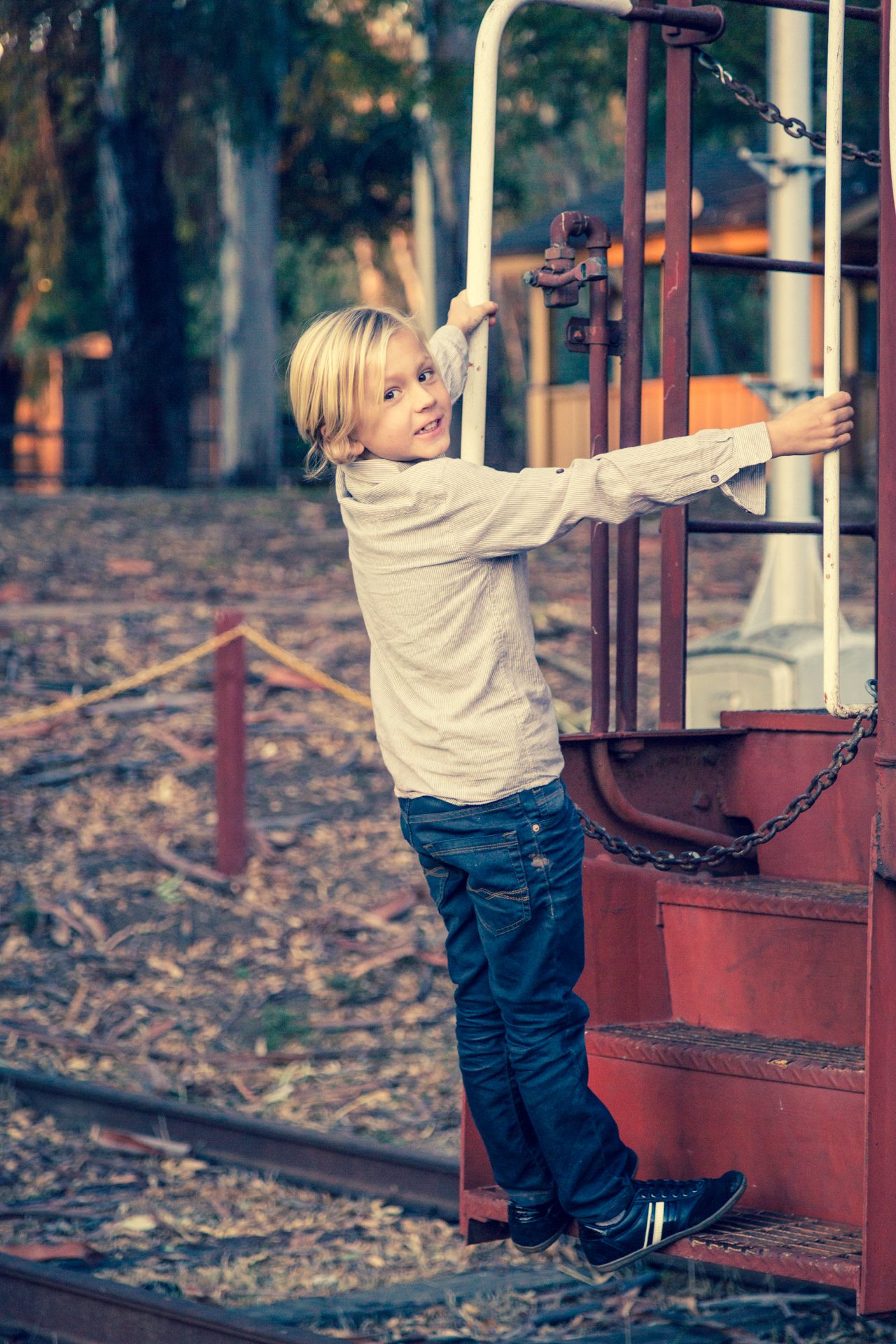 Young boy grinning back at the camera as he climbs the steps of a red caboose