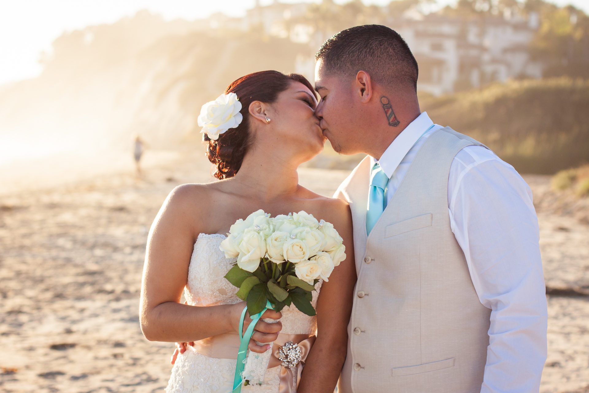 Bride and groom kissing on the beach in golden late-afternoon light