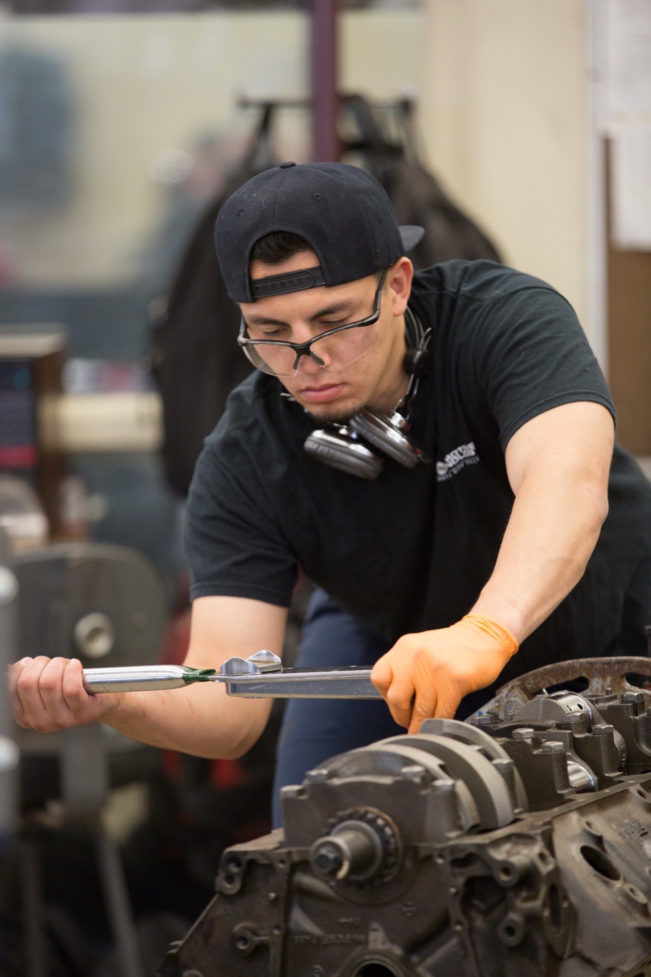 Automotive student in safety glasses tightening an engine bolt with a torque wrench