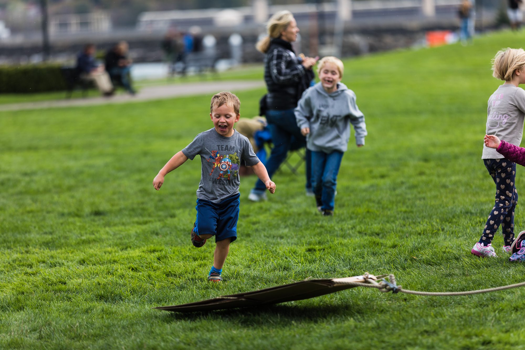 Young child laughing and running across the grass in a family play area at a festival