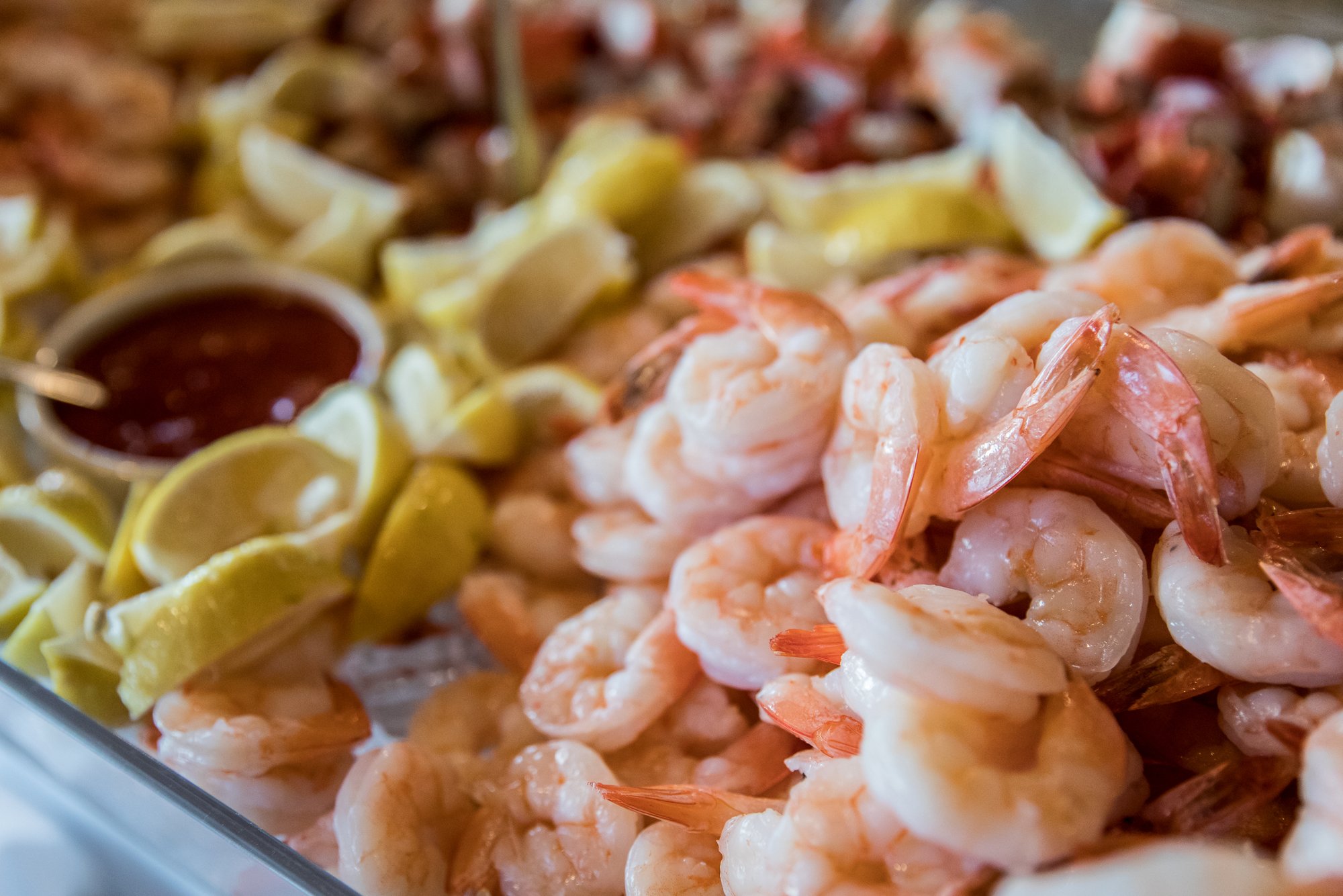 Platter of chilled shrimp with lemon wedges and cocktail sauce at a catered event