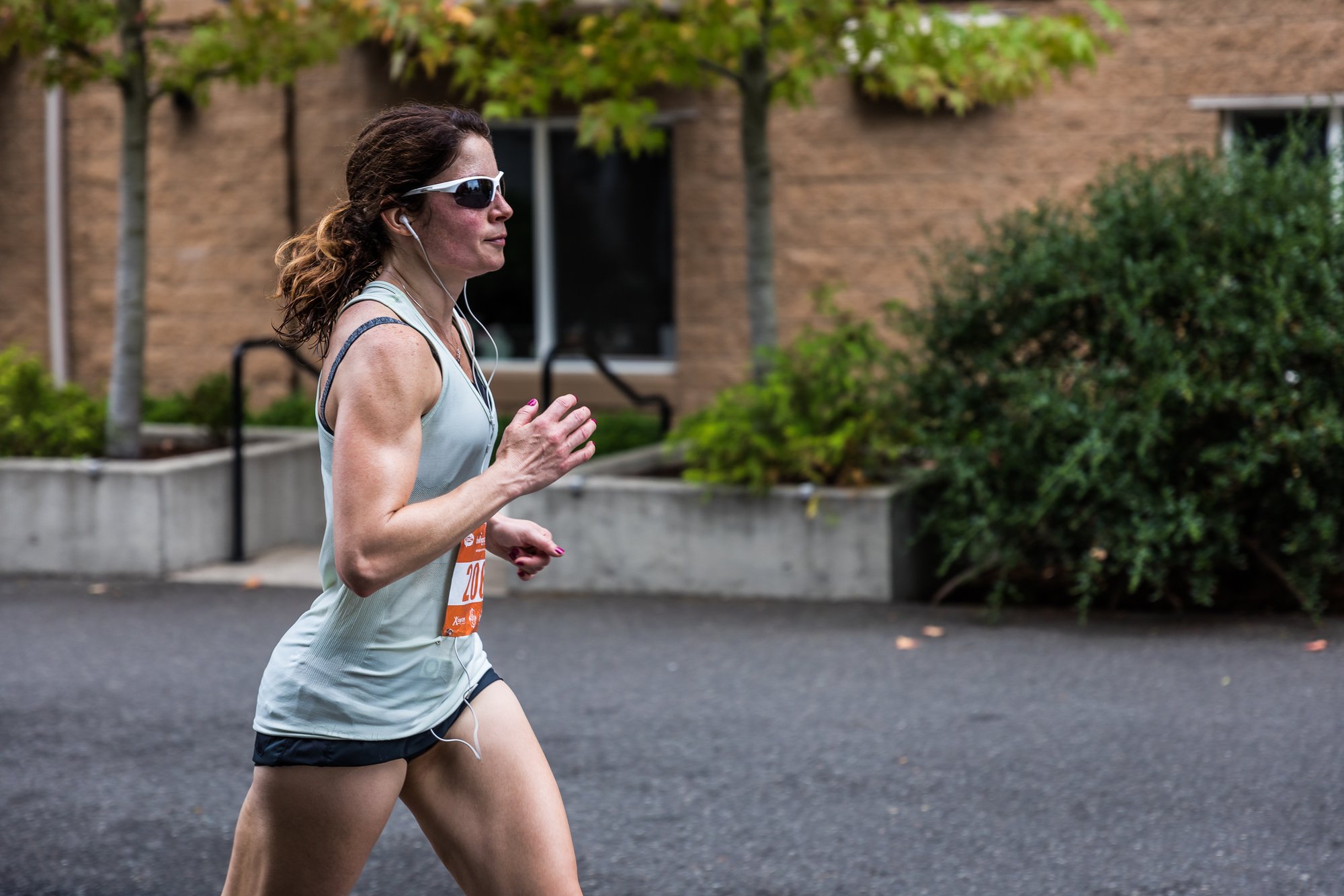 Close, tightly framed runner in sunglasses mid-stride during a road race