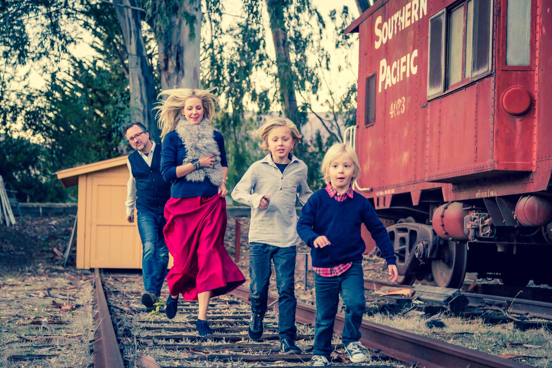 Family walking together along old railroad tracks beside a red caboose at Los Carneros in Goleta