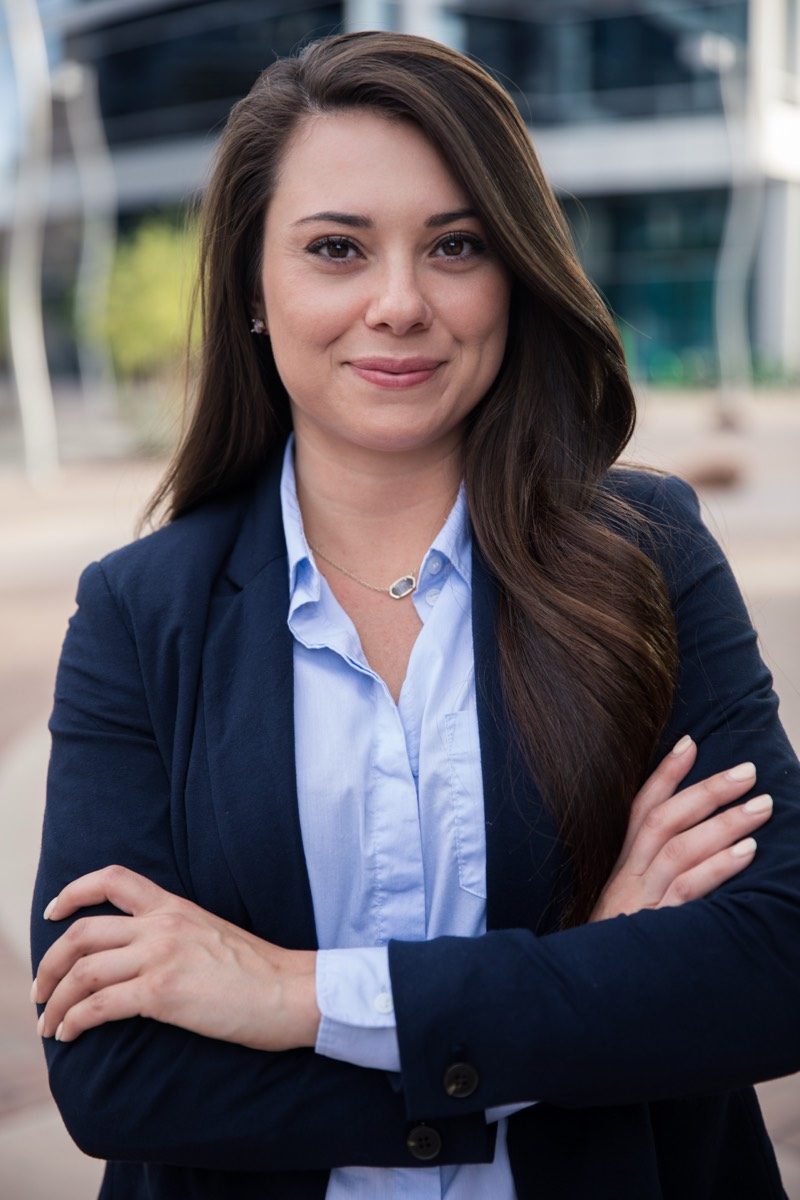 Businesswoman in a navy blazer with arms crossed outside an office building