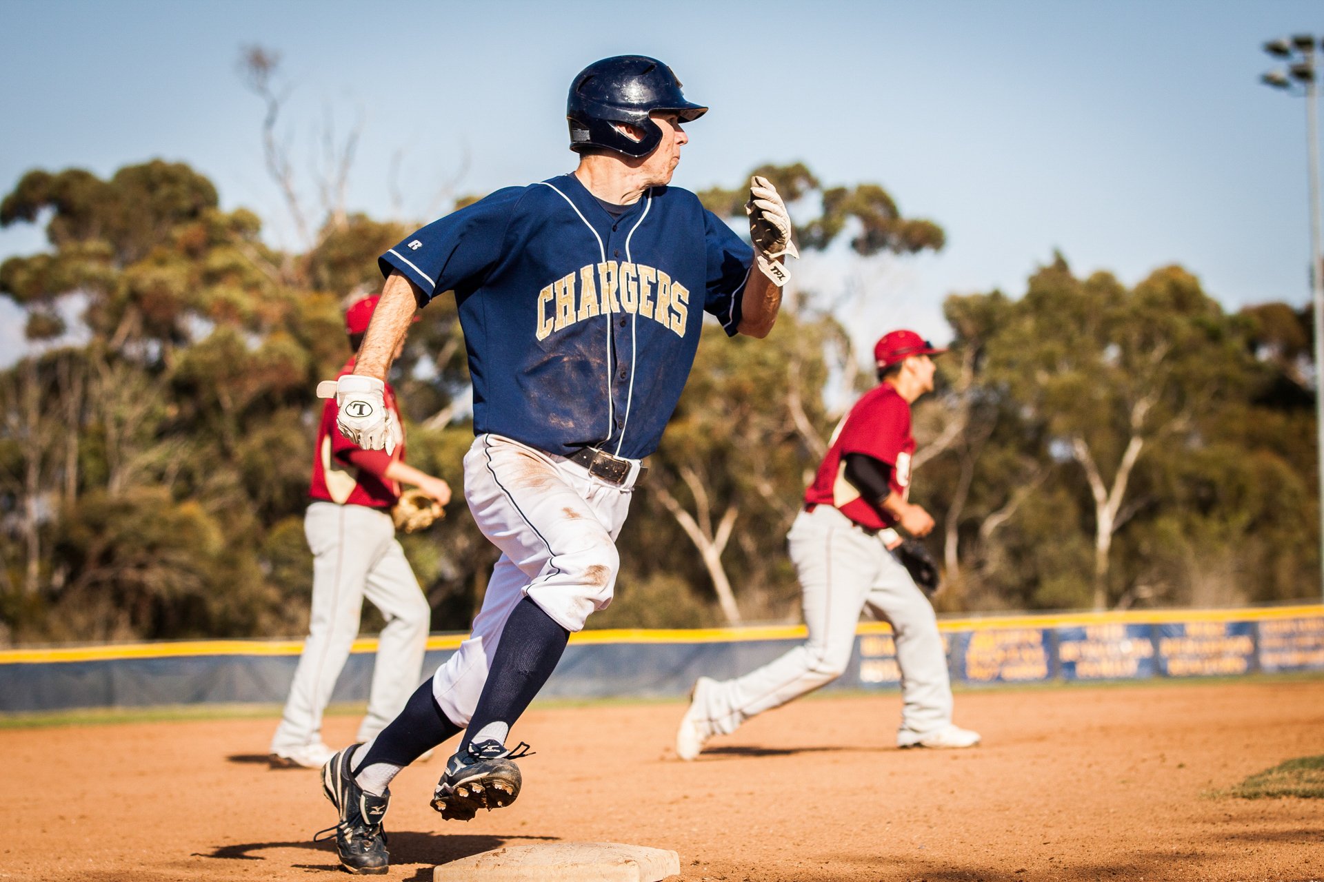 Baseball runner sprinting toward first base as the defense reacts